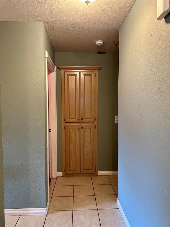 hall with light tile patterned floors and a textured ceiling