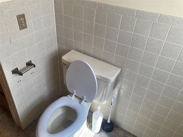 bathroom with toilet and tile walls