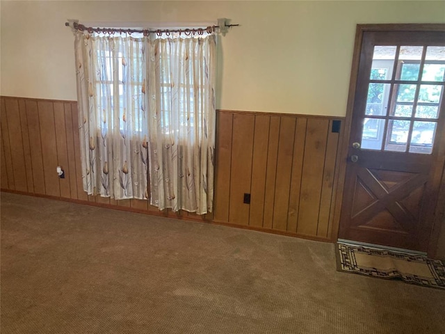 doorway with carpet floors and wooden walls