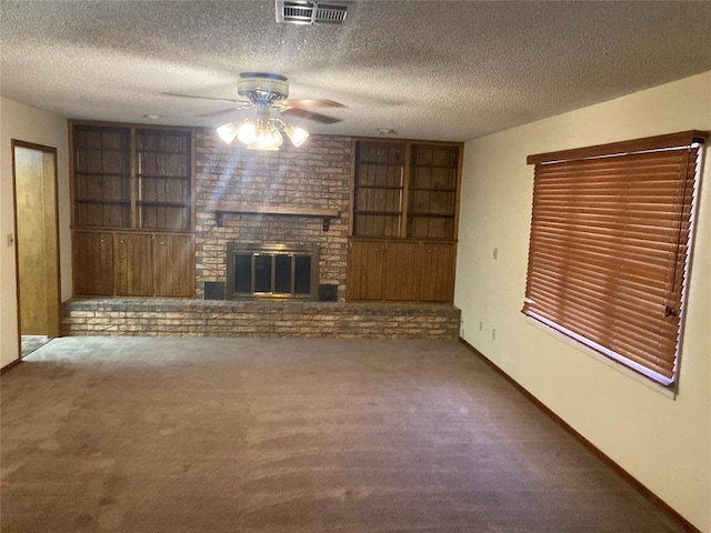 unfurnished living room featuring ceiling fan, a fireplace, a textured ceiling, and dark colored carpet