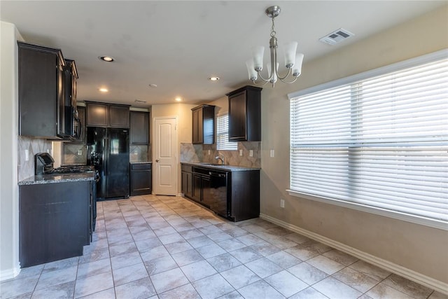 kitchen featuring sink, an inviting chandelier, backsplash, dark stone counters, and black appliances