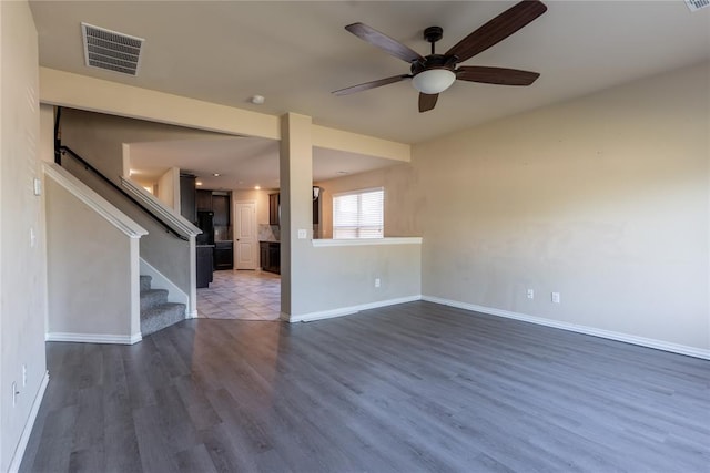 unfurnished living room featuring ceiling fan and dark wood-type flooring