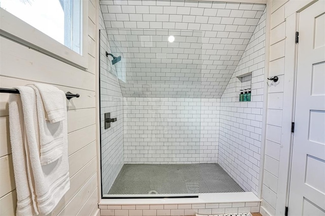 bathroom featuring tiled shower and wooden walls