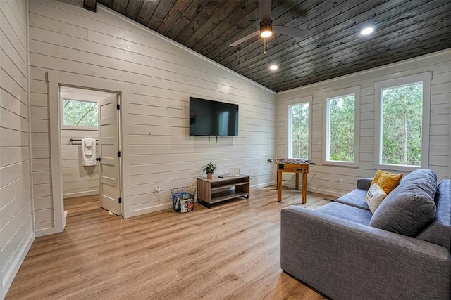 living room with wood walls, light hardwood / wood-style floors, and vaulted ceiling