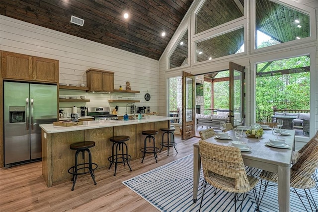 kitchen with a breakfast bar area, light hardwood / wood-style flooring, high vaulted ceiling, and appliances with stainless steel finishes