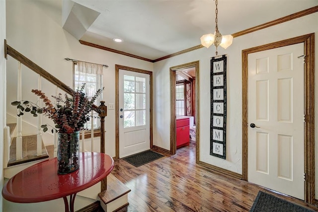 entrance foyer featuring hardwood / wood-style flooring, ornamental molding, and a chandelier