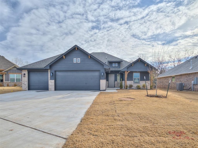 view of front of home with central AC, a garage, and a front lawn