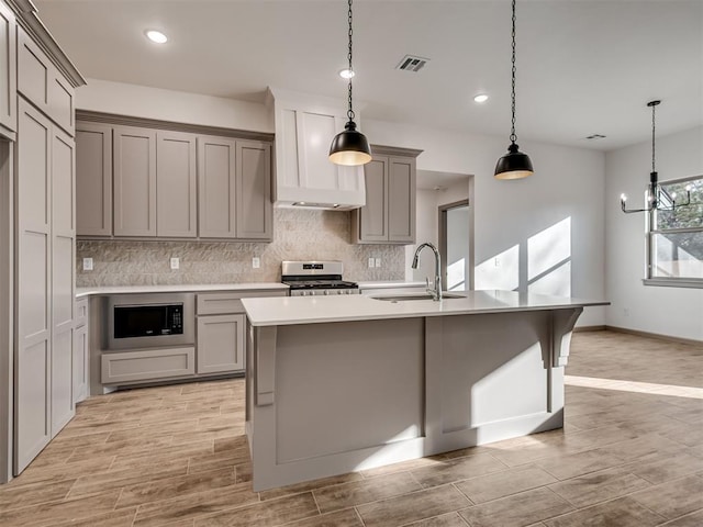 kitchen featuring pendant lighting, sink, gray cabinetry, black microwave, and stainless steel range oven