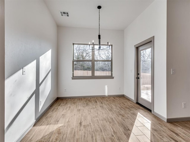 unfurnished dining area with a notable chandelier and light wood-type flooring