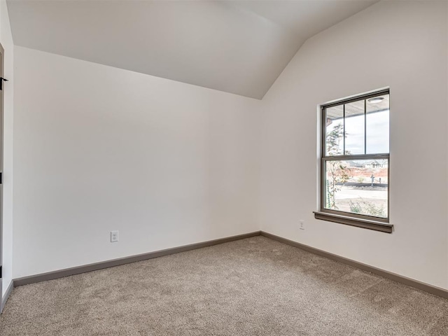 unfurnished room featuring lofted ceiling and carpet