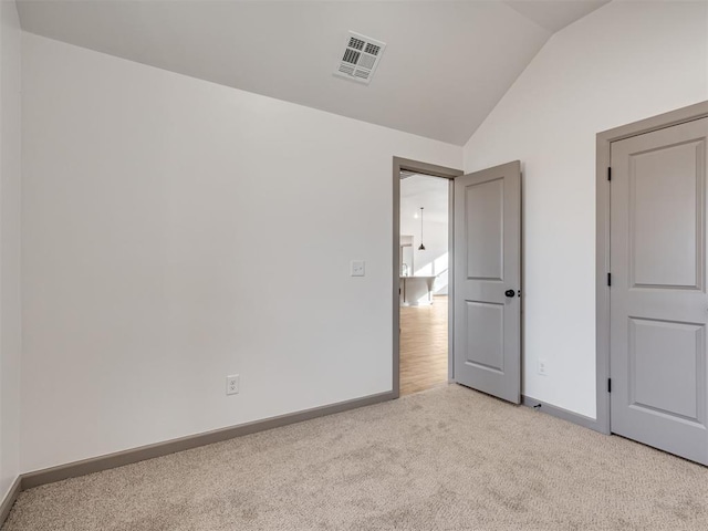 unfurnished bedroom featuring lofted ceiling and light carpet