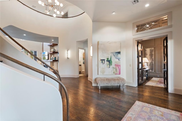 foyer entrance with dark hardwood / wood-style flooring, a towering ceiling, and a chandelier