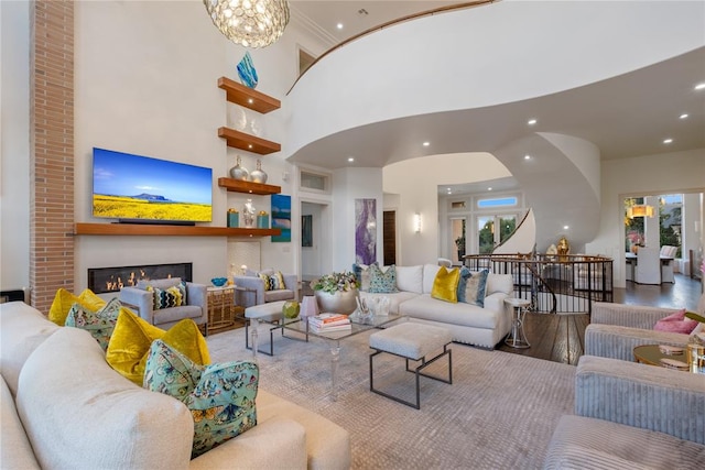 living room featuring ornamental molding, light hardwood / wood-style floors, a high ceiling, and an inviting chandelier