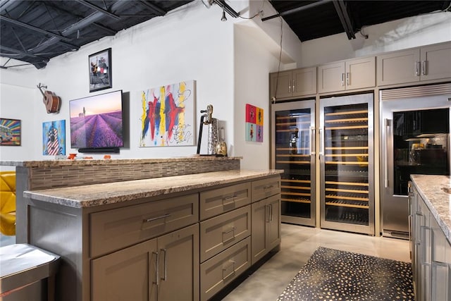 bar with gray cabinets, light stone countertops, and stainless steel built in refrigerator