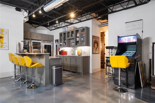 kitchen featuring kitchen peninsula, sink, a high ceiling, built in refrigerator, and a breakfast bar area