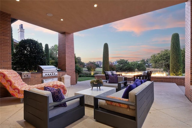 patio terrace at dusk featuring area for grilling, grilling area, and an outdoor living space with a fire pit