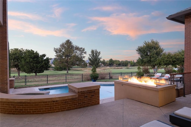 pool at dusk with an in ground hot tub, a patio, and an outdoor fire pit