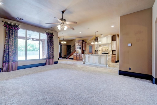 unfurnished living room featuring light colored carpet and ceiling fan with notable chandelier