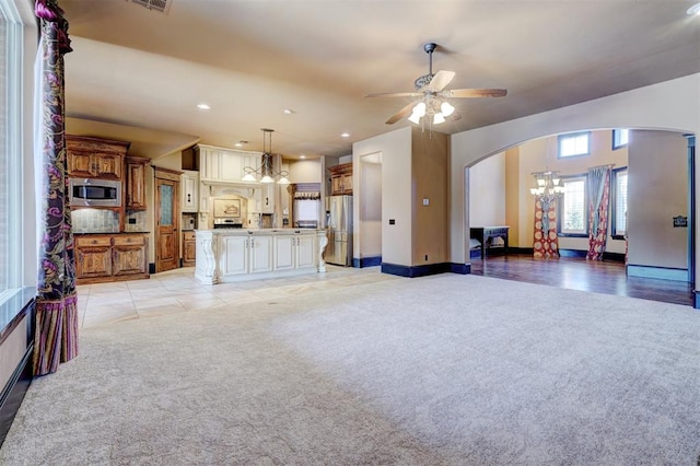 carpeted living room with ceiling fan with notable chandelier