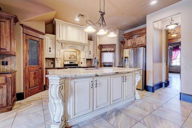 kitchen with decorative backsplash, appliances with stainless steel finishes, sink, a center island with sink, and hanging light fixtures