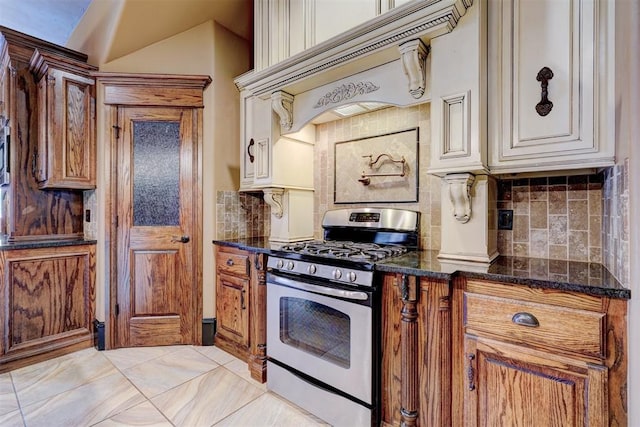 kitchen with custom range hood, gas stove, dark stone countertops, and backsplash