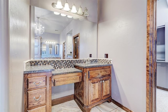 bathroom with a notable chandelier, vanity, backsplash, and tile patterned floors