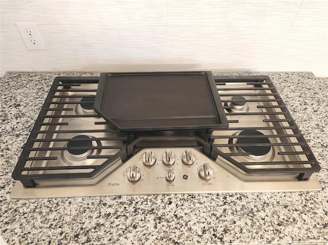 details featuring light stone counters and stainless steel gas stovetop