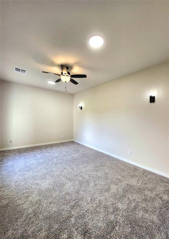 carpeted spare room featuring ceiling fan