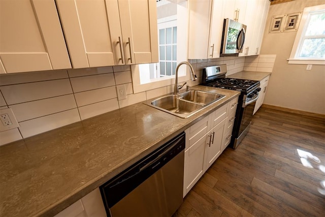 kitchen featuring appliances with stainless steel finishes, backsplash, sink, white cabinets, and dark hardwood / wood-style floors