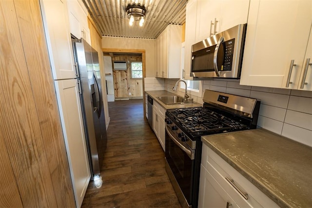 kitchen with appliances with stainless steel finishes, dark hardwood / wood-style floors, white cabinetry, and sink