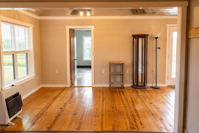 interior space featuring heating unit, light hardwood / wood-style flooring, and crown molding