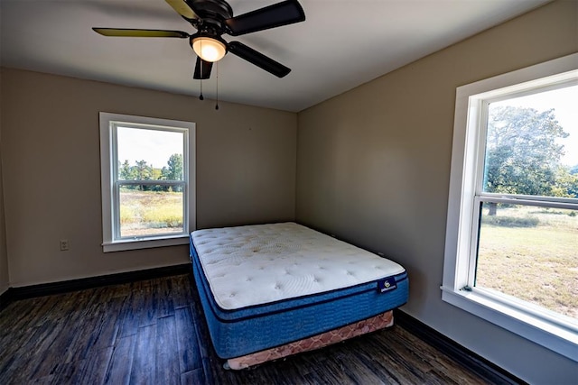 unfurnished bedroom featuring ceiling fan, dark hardwood / wood-style flooring, and multiple windows