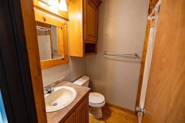 bathroom featuring a shower with curtain, vanity, hardwood / wood-style flooring, and toilet