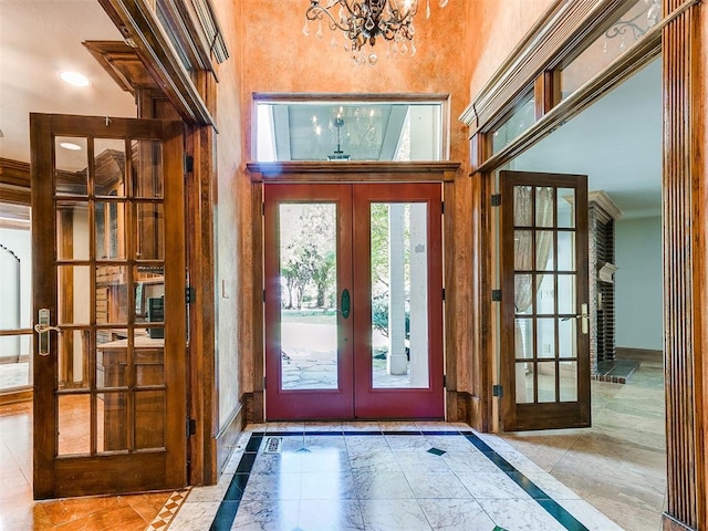 doorway featuring french doors, ornamental molding, and a notable chandelier