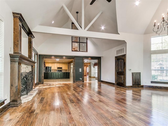 unfurnished living room with hardwood / wood-style floors, high vaulted ceiling, and beam ceiling