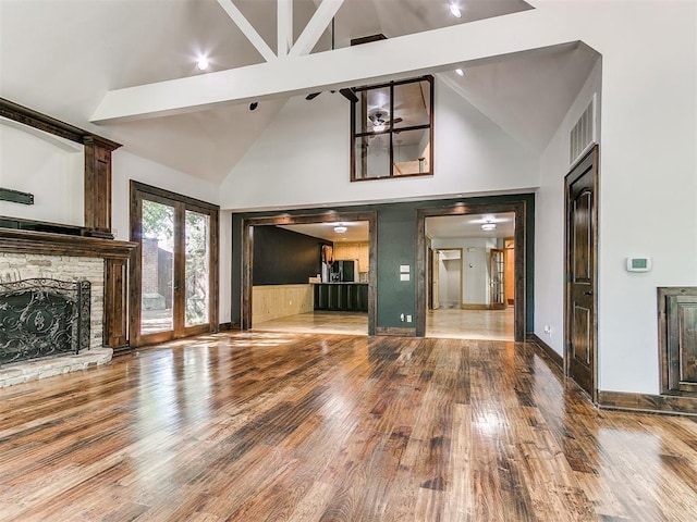 unfurnished living room featuring a fireplace, hardwood / wood-style floors, beamed ceiling, and high vaulted ceiling