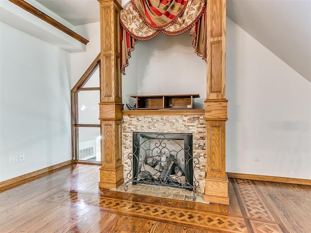 living room with a tiled fireplace, vaulted ceiling, and hardwood / wood-style flooring