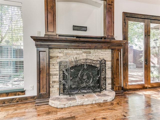 interior details featuring a stone fireplace, hardwood / wood-style floors, and french doors