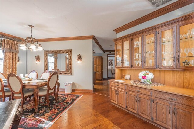 dining area with crown molding, dark hardwood / wood-style flooring, and an inviting chandelier