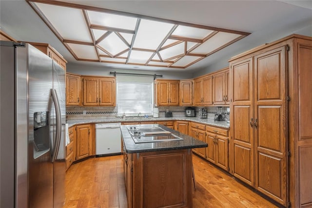 kitchen with tasteful backsplash, a kitchen island, stainless steel appliances, and light hardwood / wood-style floors