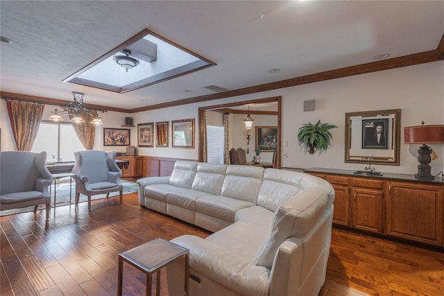 living room with a skylight, crown molding, and dark hardwood / wood-style flooring