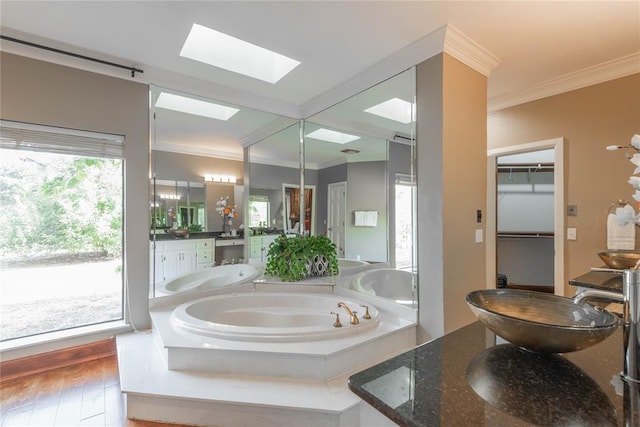 bathroom with a skylight, wood-type flooring, a bathtub, vanity, and ornamental molding