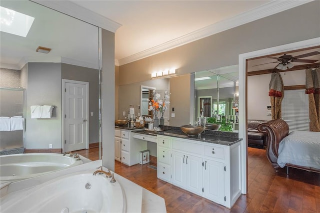 bathroom featuring a skylight, ornamental molding, vanity, ceiling fan, and hardwood / wood-style floors