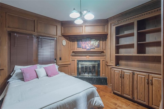 bedroom featuring a high end fireplace, light wood-type flooring, and a notable chandelier