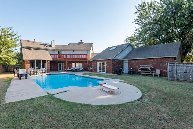 view of swimming pool with a diving board, a patio area, and a yard