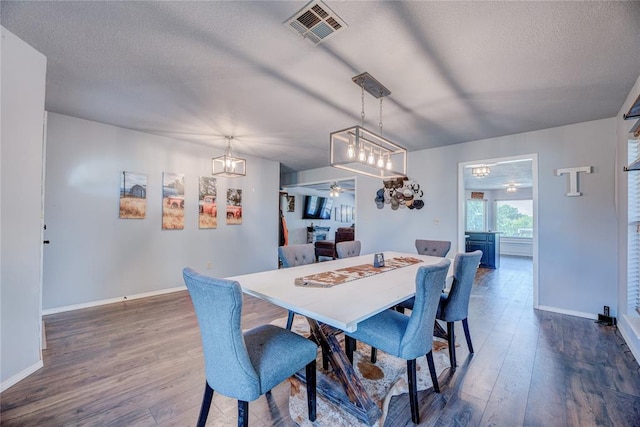 dining area with ceiling fan, dark hardwood / wood-style floors, and a textured ceiling