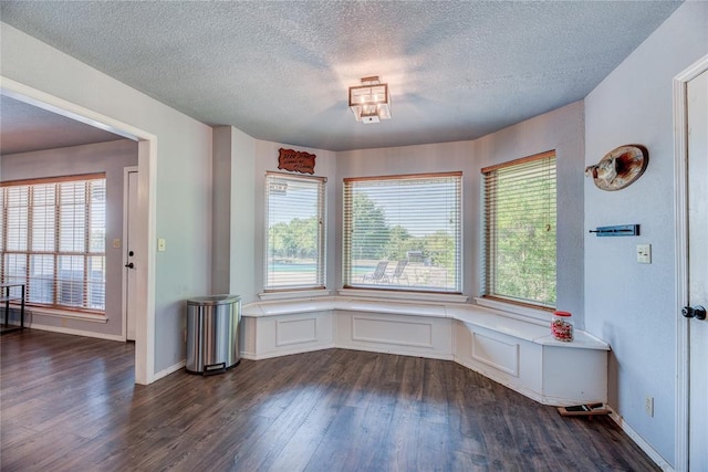 unfurnished dining area with dark wood-type flooring and a textured ceiling