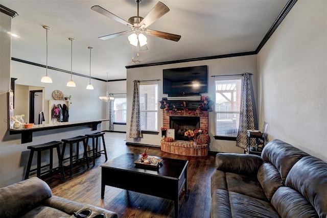 living room with hardwood / wood-style floors, ceiling fan with notable chandelier, sink, crown molding, and a brick fireplace