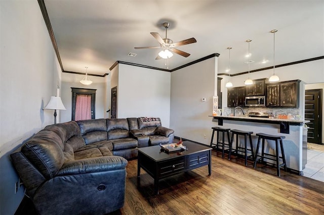 living room with light hardwood / wood-style flooring, ceiling fan, crown molding, and sink