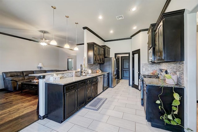 kitchen with pendant lighting, backsplash, sink, appliances with stainless steel finishes, and light stone counters